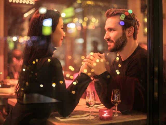 Couple holding hands and looking happy at dinner table