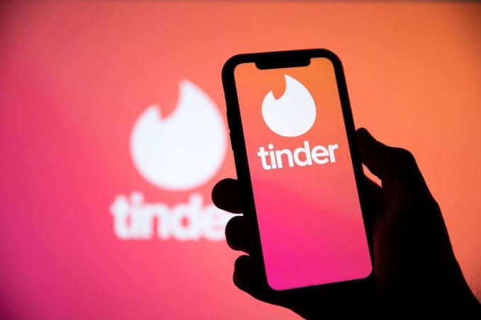 Tinder logo on phone screen and in background